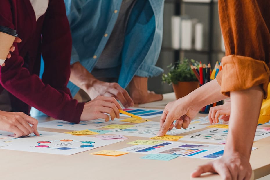 Business men and women meeting and brainstorming ideas about design, planning, and strategy for application development and template layouts while working together on project execution in a small office.
