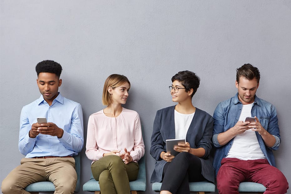 Busy business people, wait for meeting with boss: two guys chattes over cell phone or surf social networks and women have pleasant conversation, make acquintance, find common topic to discuss
